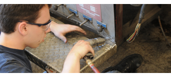 A student does maintenance work on a diesel truck.